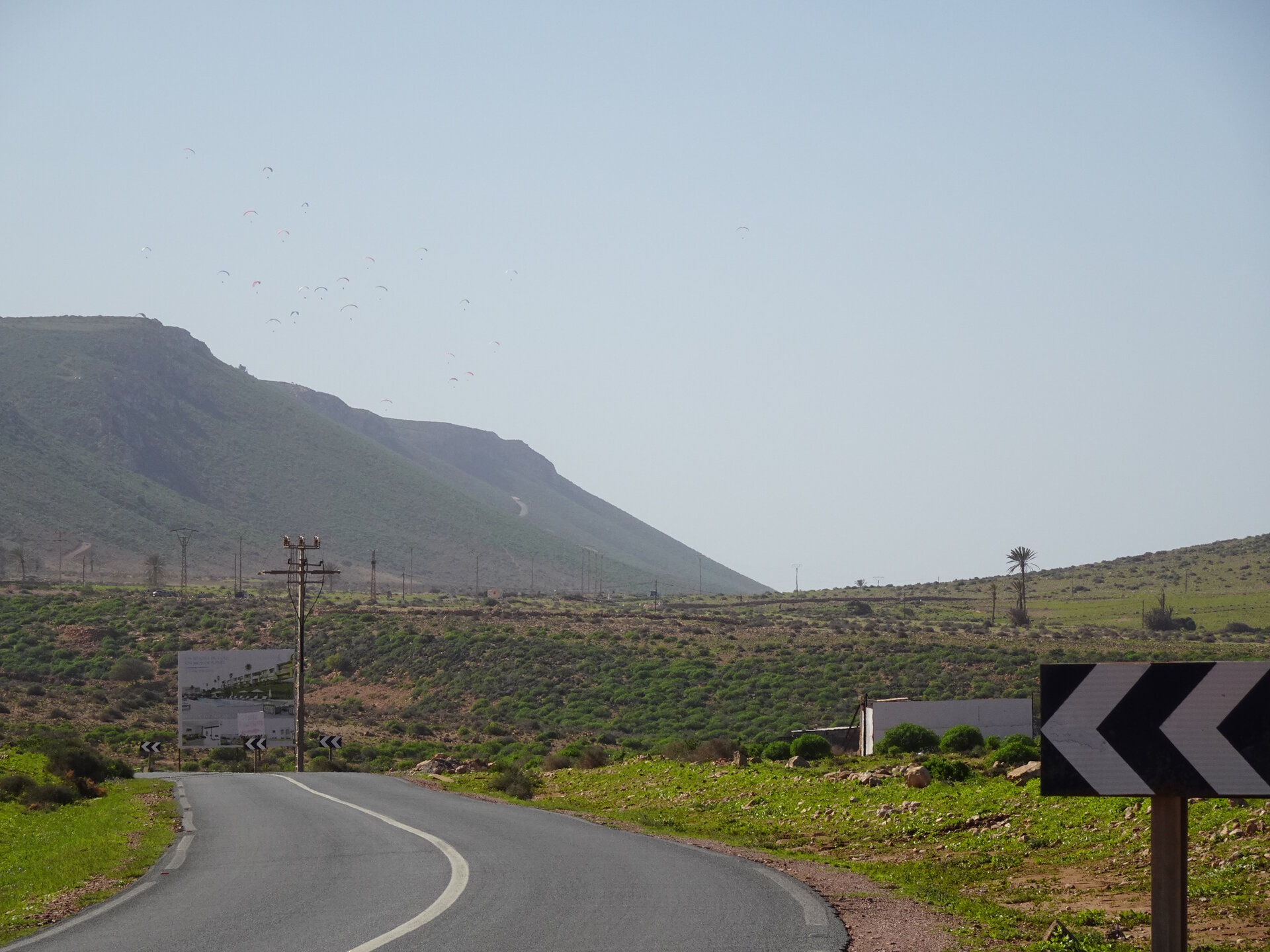 Coastal road with paragliders in background