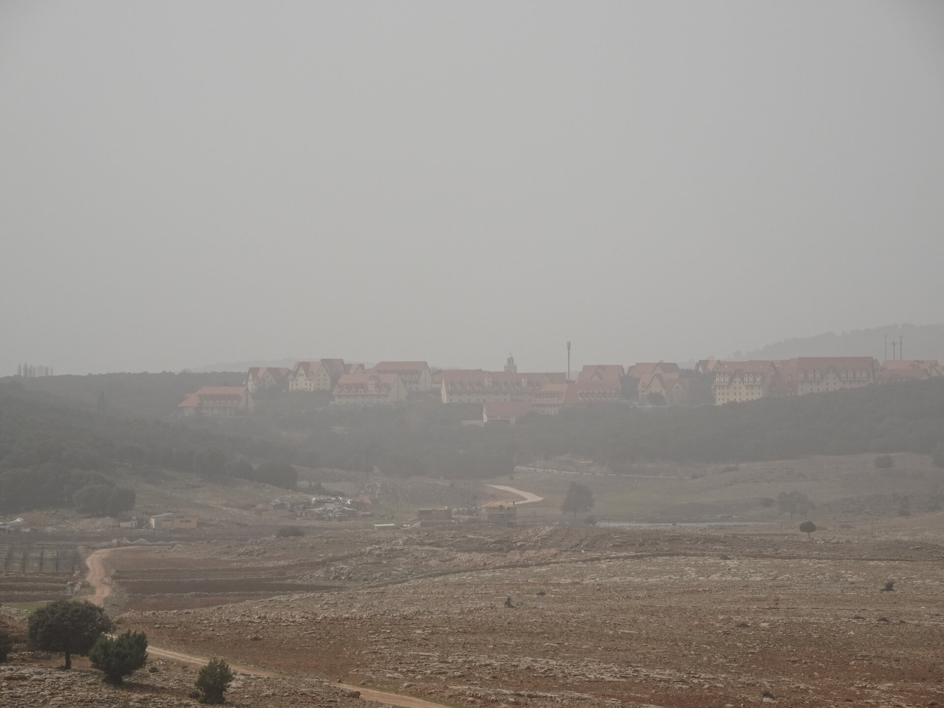 European-style buildings on a distant hilltop seen through haze