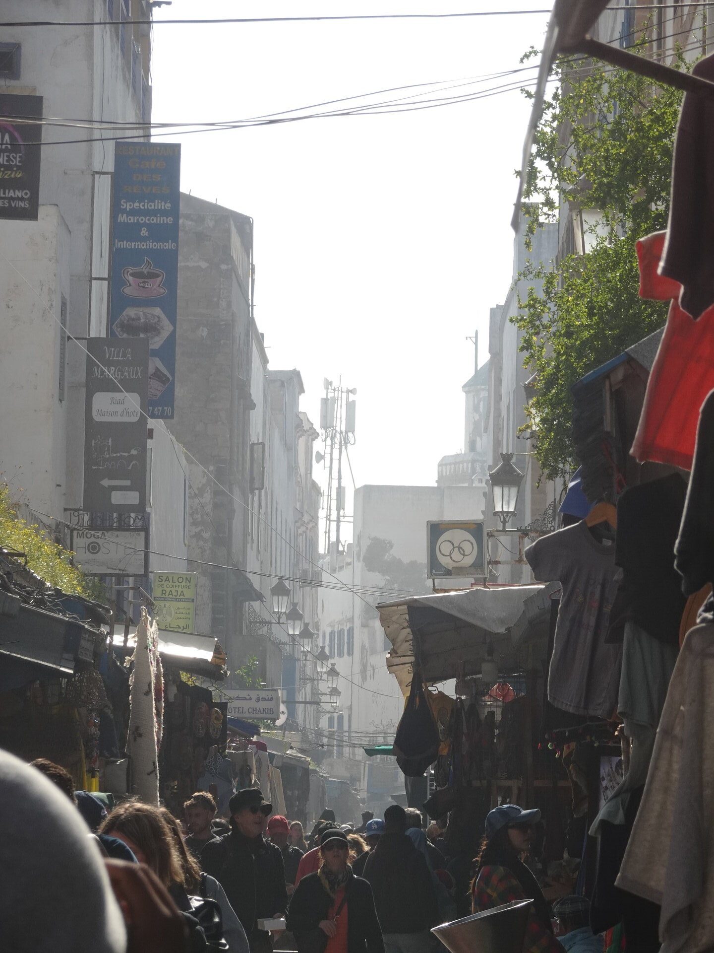 Crowded medina street with restaurant signs and clothing stalls