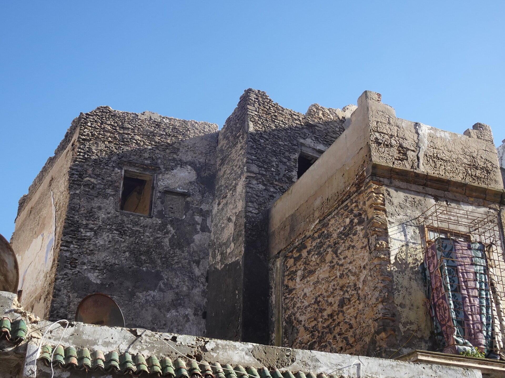 Weathered stone buildings with exposed walls and draped fabrics in the old medina