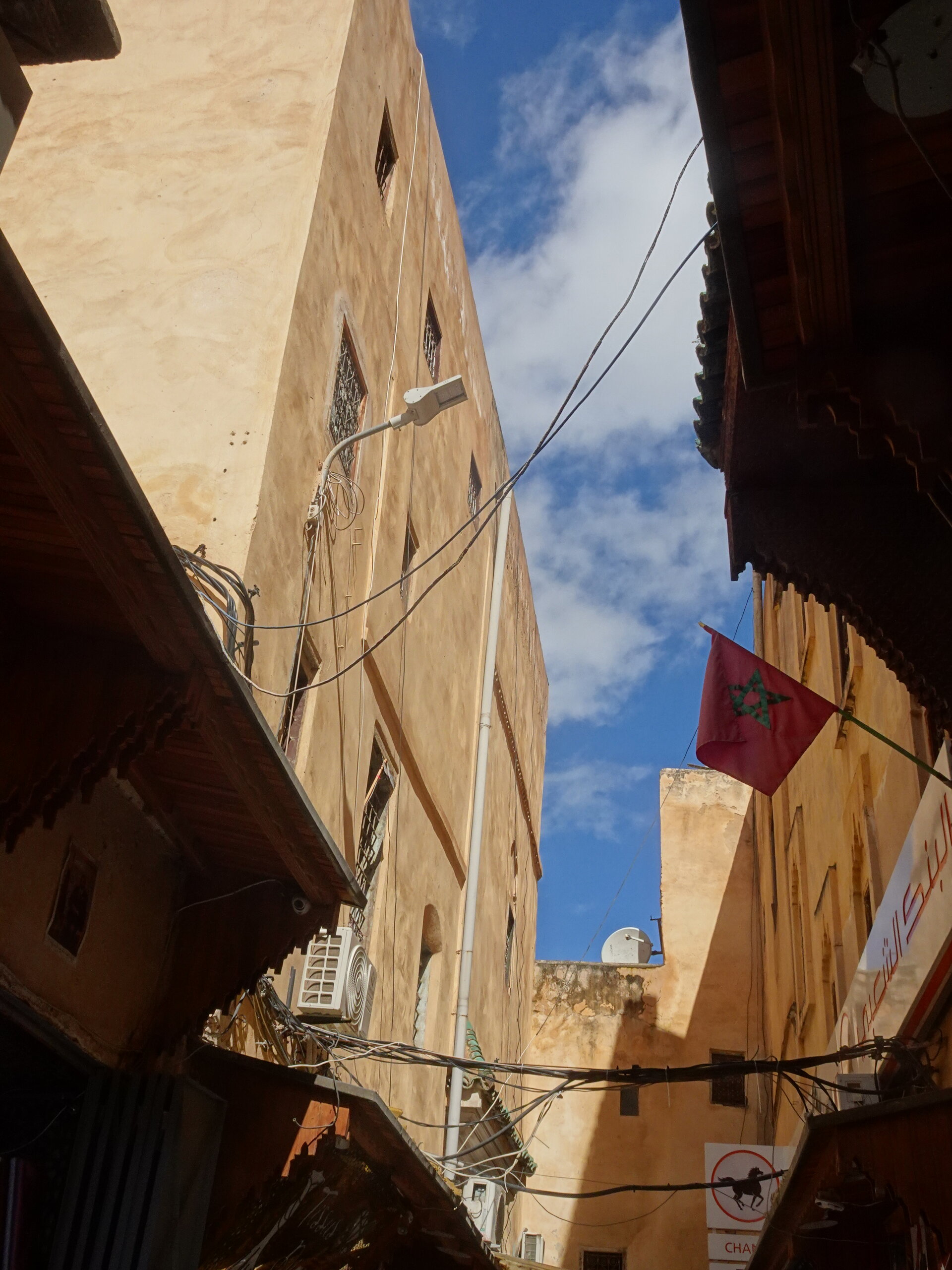 Moroccan flag hanging between sand-coloured buildings in the medina