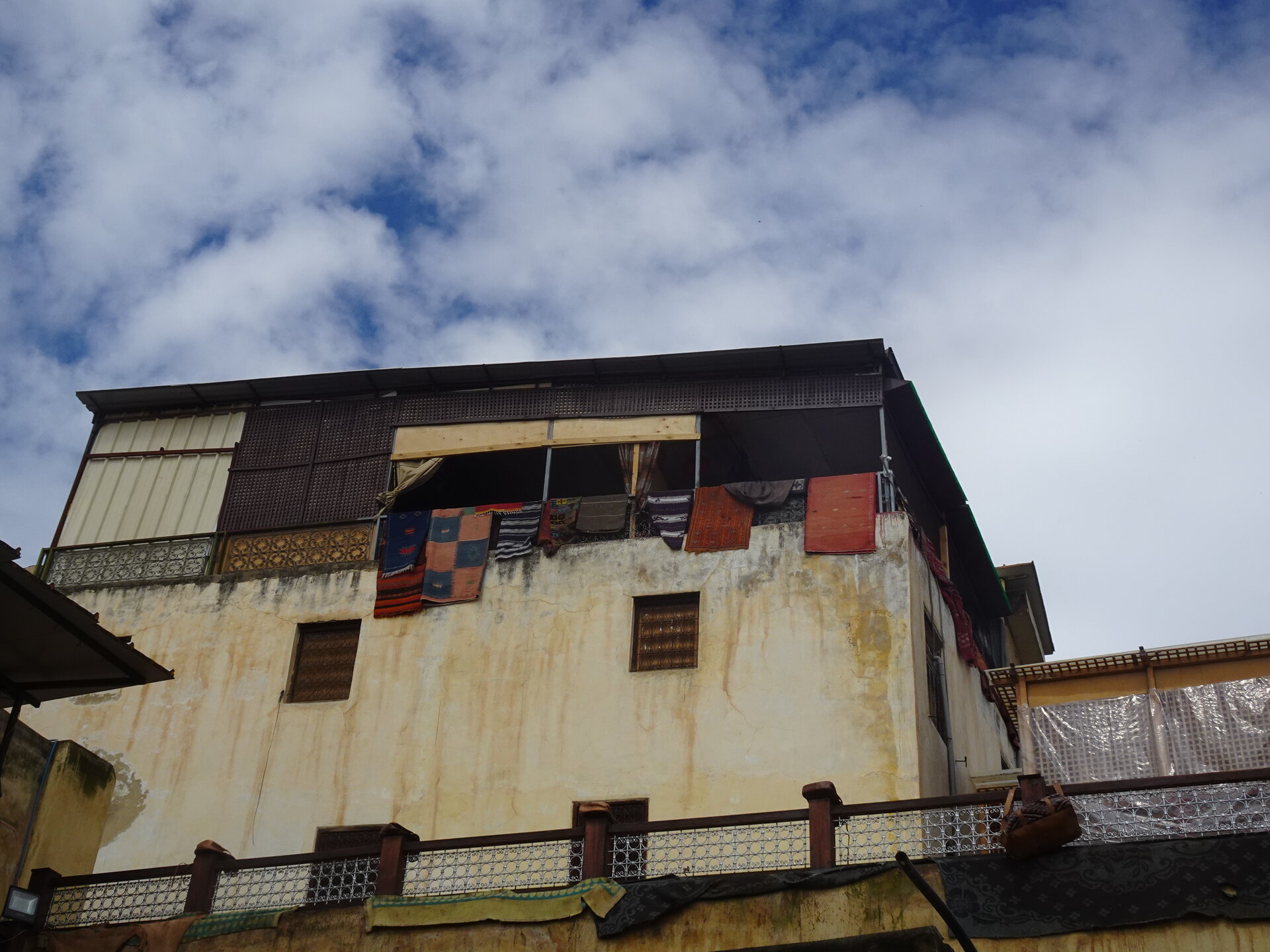 Colourful rugs and leather goods hanging from a building above the tannery