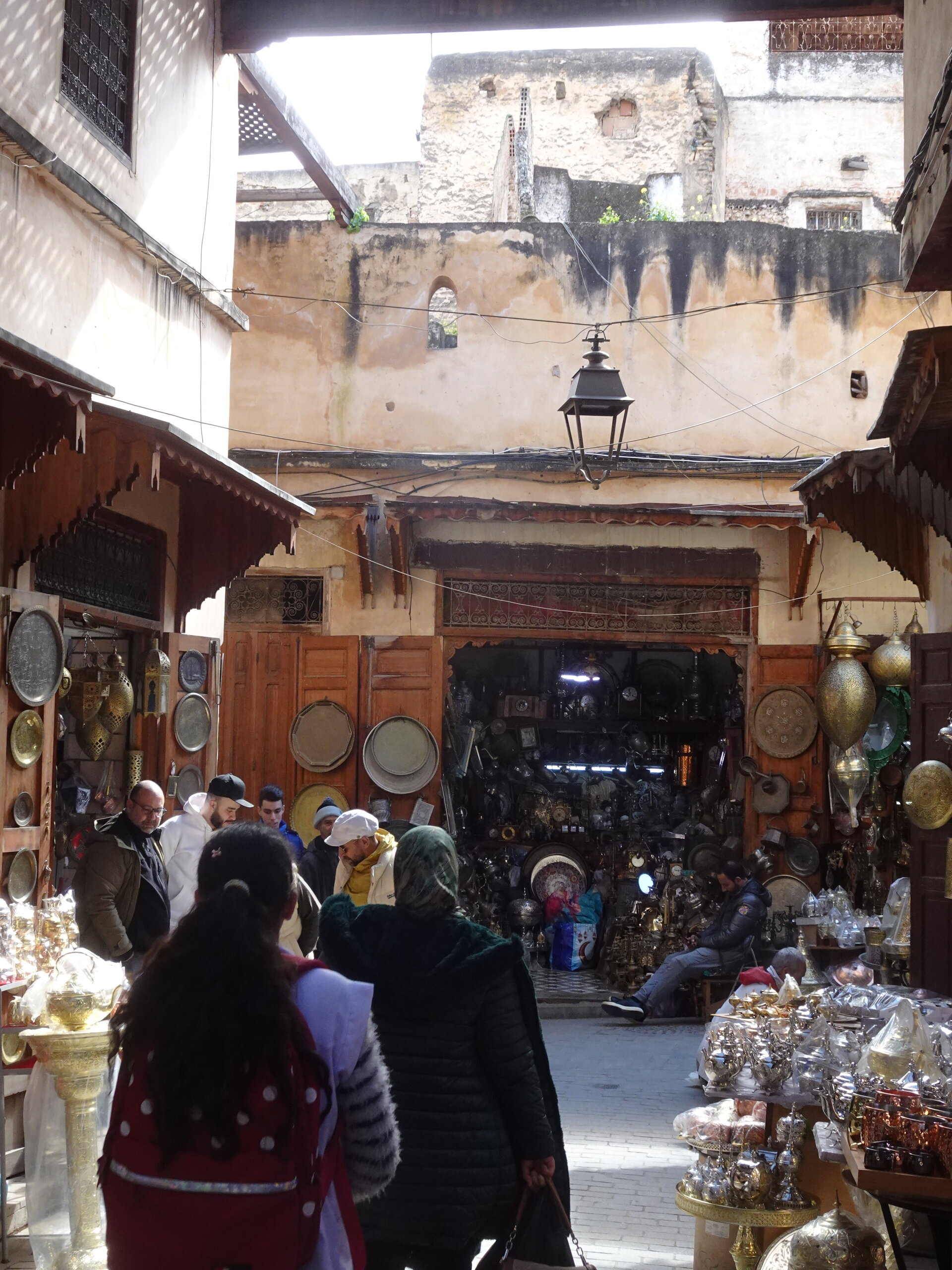 Crowded souk with metalwork shops selling brass plates and lanterns