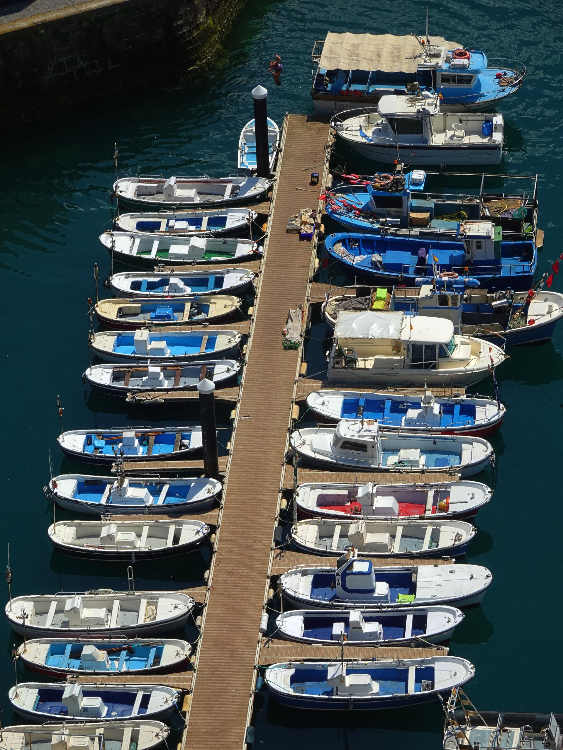Rows of small fishing boats moored along a wooden jetty in the harbour