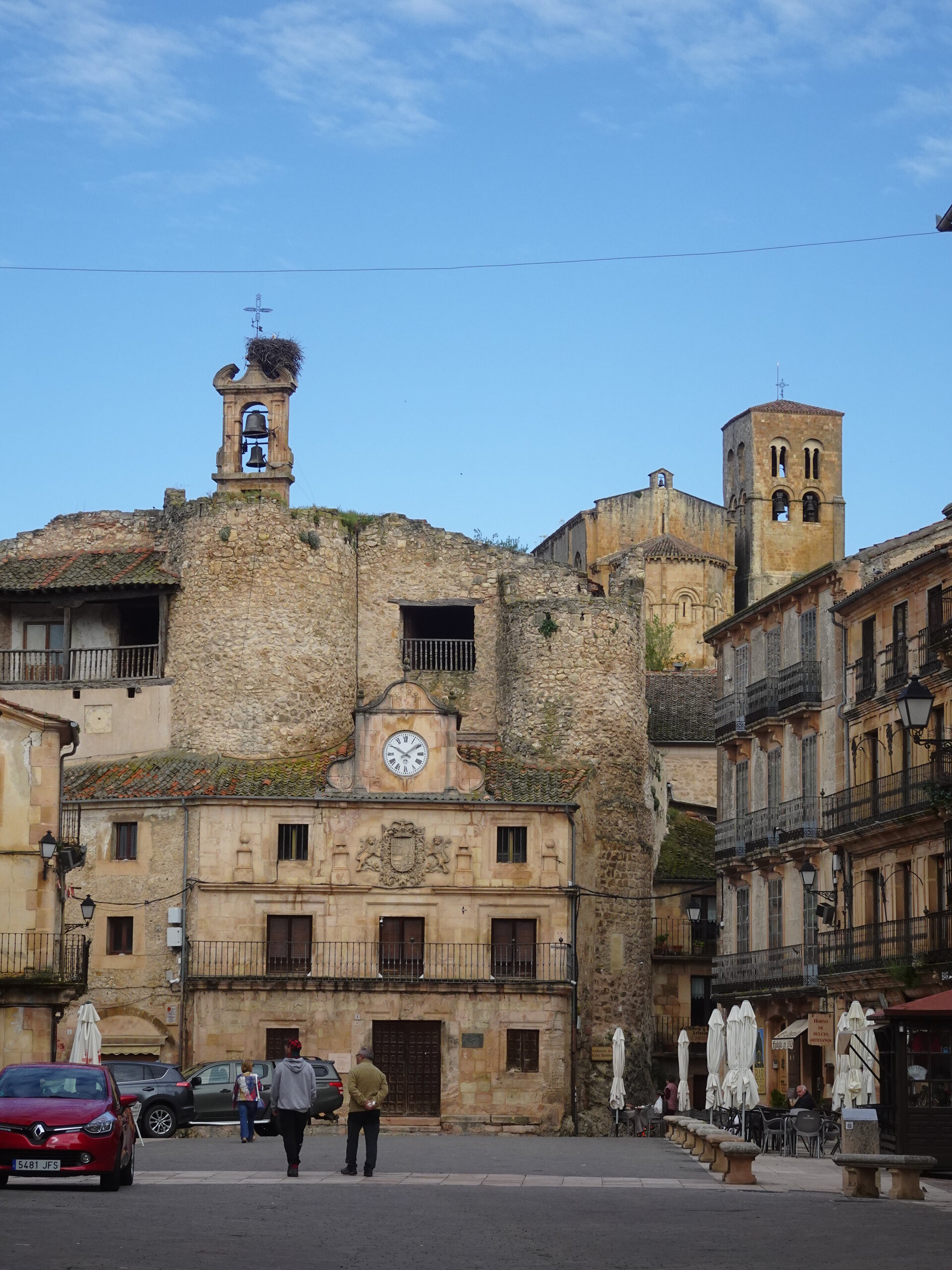 Stone medieval town square with a clock tower and bell tower under a blue sky