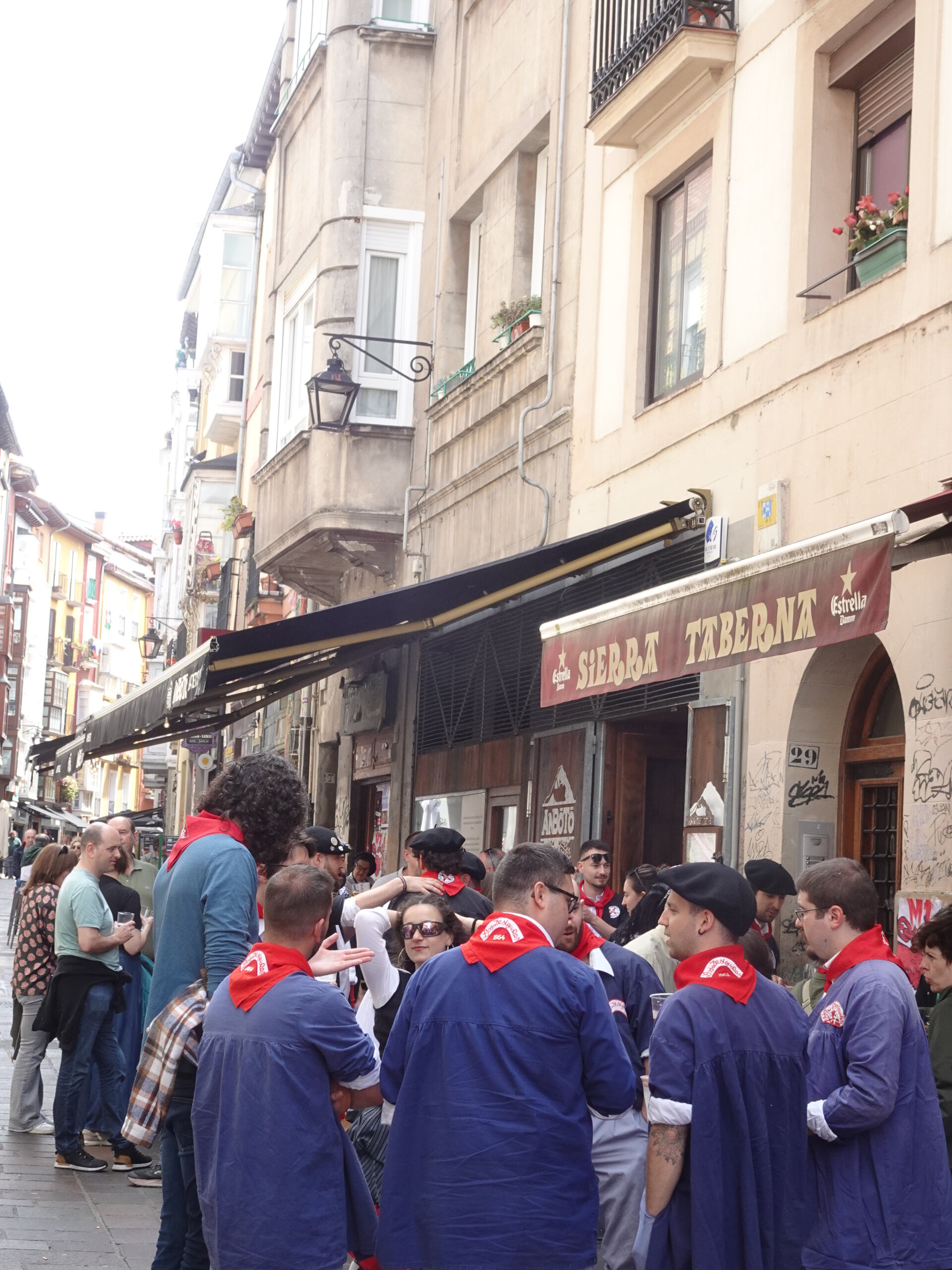 Crowd in blue smocks and red scarves outside a bar during a festival