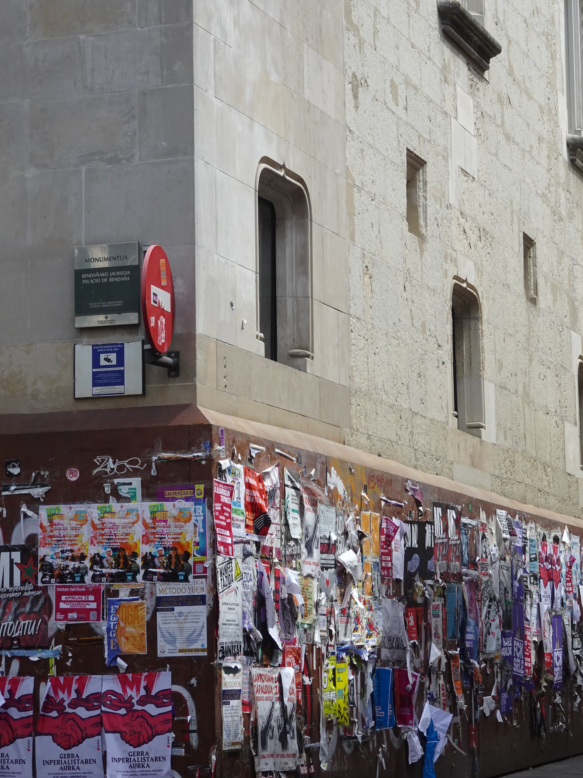 Stone building corner with a wall plastered in layered posters