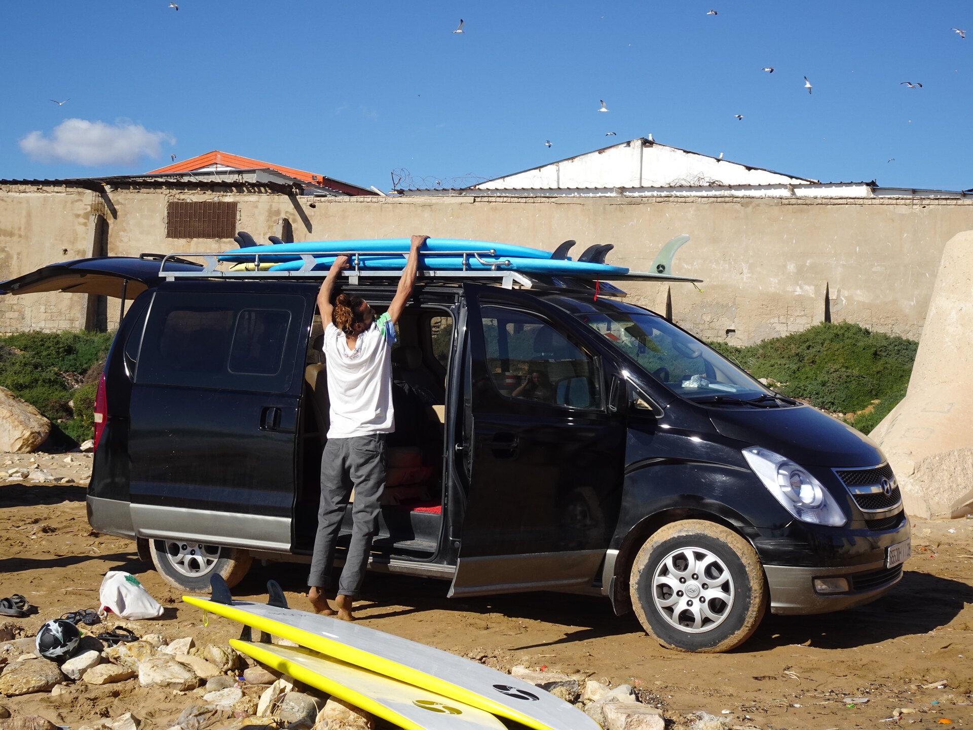 Man putting surfboard on the roof of a car