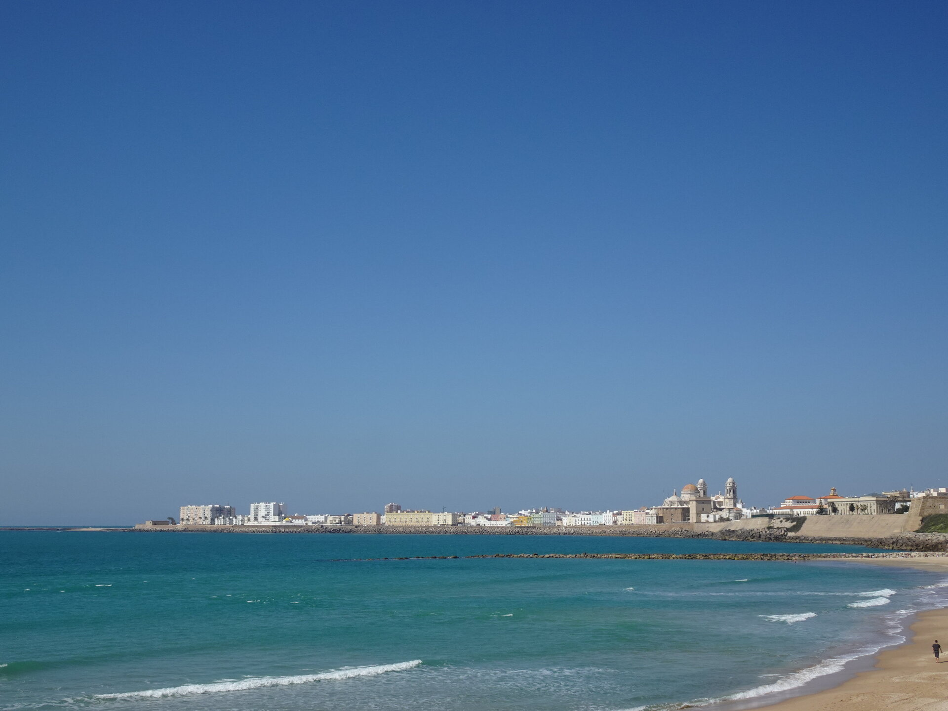 Turquoise sea with Cadiz old town and cathedral on the horizon