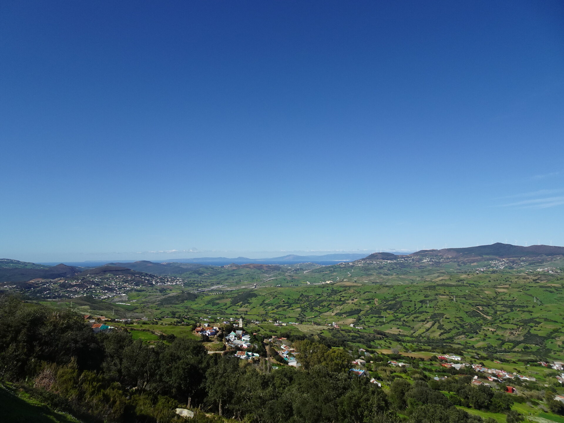 Wide view over green countryside toward the coast and Spain beyond